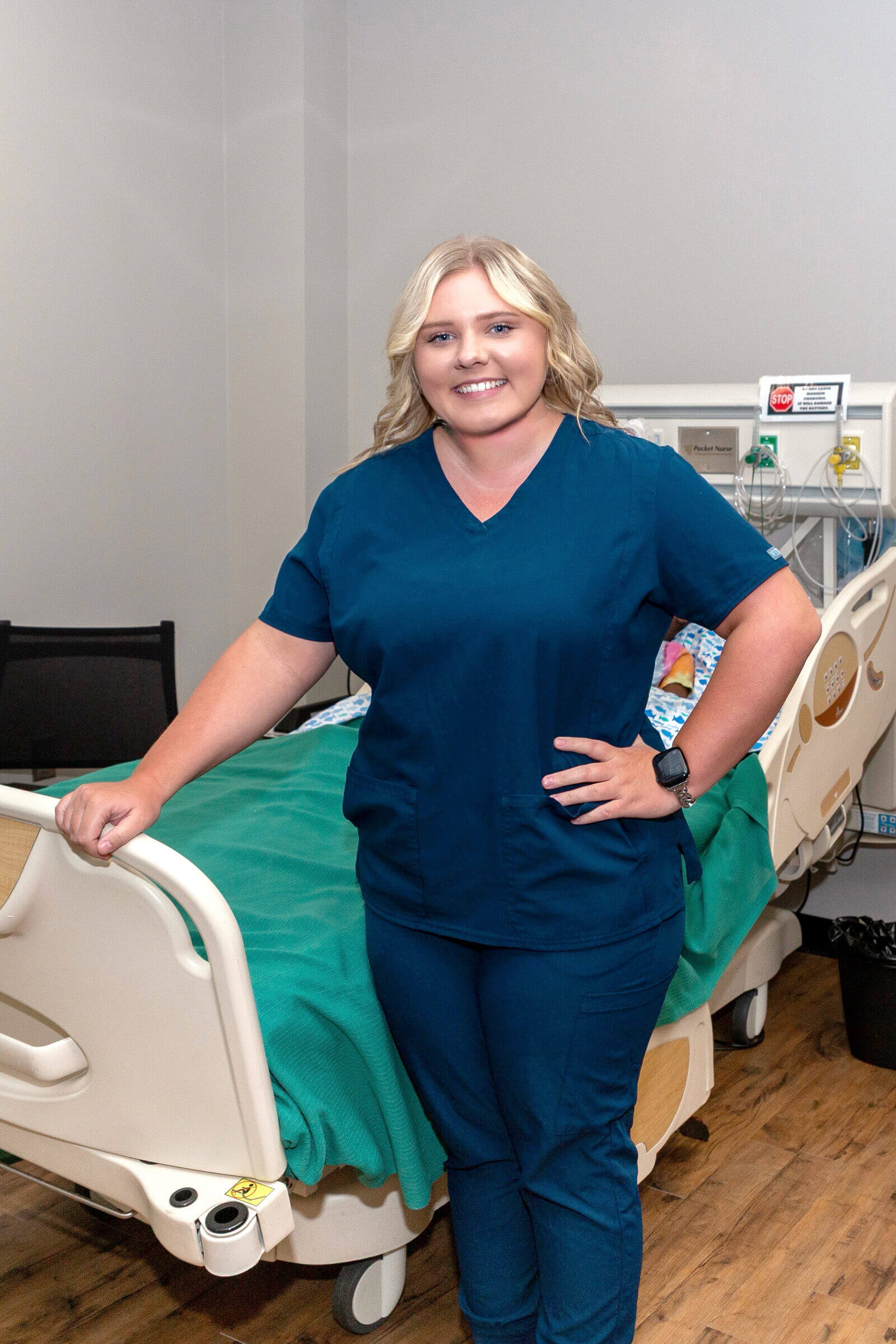 Skylar McIntosh poses at foot of bed in Sim Lab