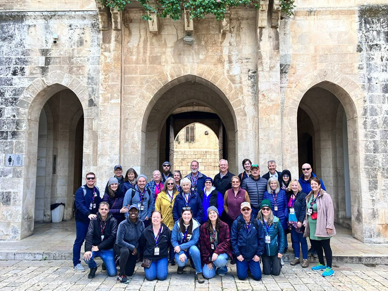 Marlee Merritt with a large group of friends outside posing for a photo outside an ancient stone archway