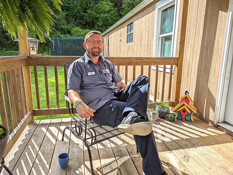 Former student DJ Vess sitting on a chair on his porch in the sunshine