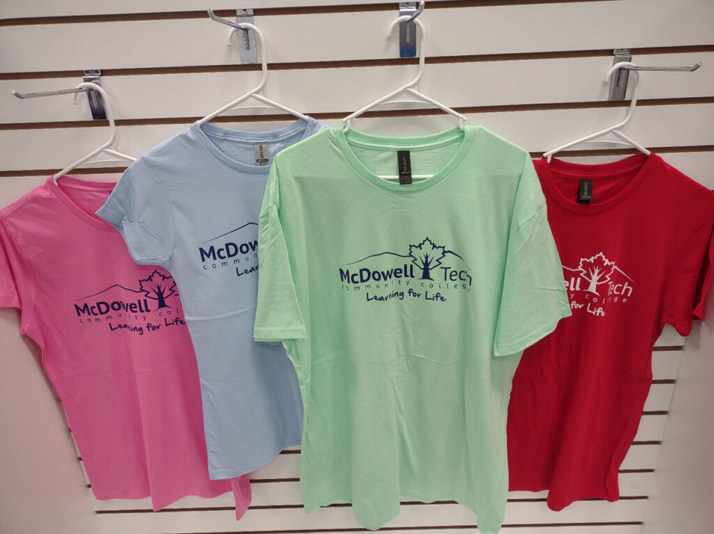 Image of the various t-shirts available this summer at the bookstore, shown in pink, blue , red, and green